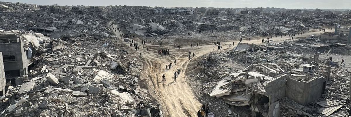 Palestinians walk through the remnants of the Jabalia refugee camp