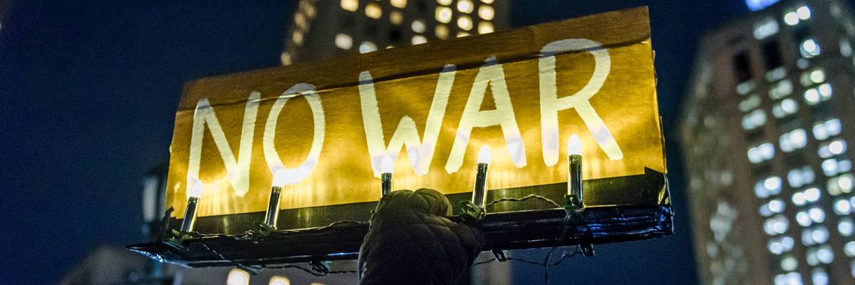 Participant holding an illuminated sign reading NO WAR at