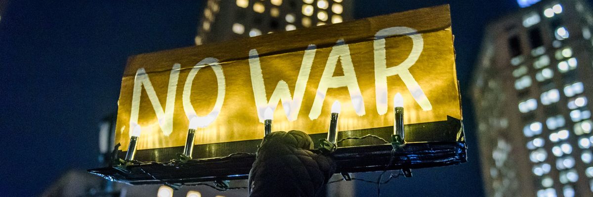 Participant holding an illuminated sign reading NO WAR at