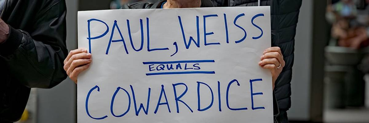 Participant seen holding a sign outside Paul, Weiss law firm that reads, "Paul, Weiss = cowardice."