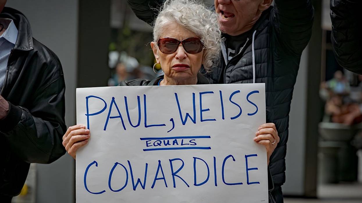 Participant seen holding a sign outside Paul, Weiss law firm that reads, "Paul, Weiss = cowardice."