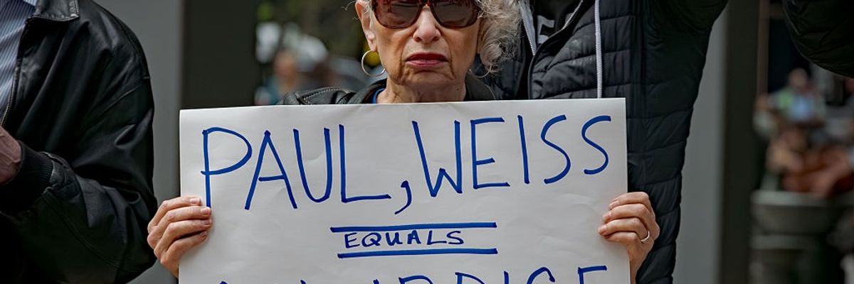 Participant seen holding a sign outside Paul, Weiss law firm...