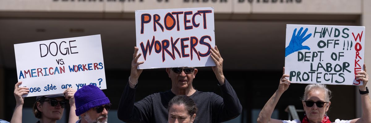 Participants hold signs during a news conference with Federal Workers Against DOGE