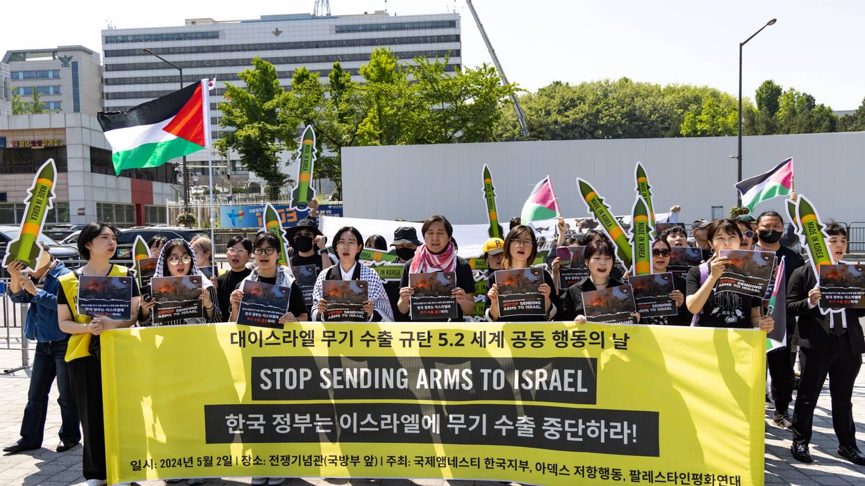 Participants hold signs that read, "Korean Government: Stop Arms Exports to Israel"