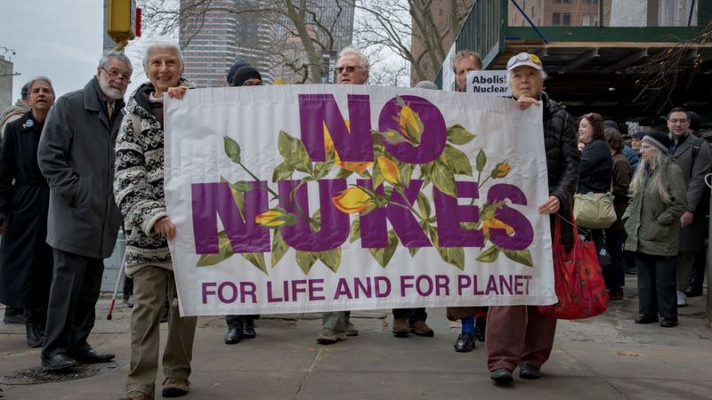 Participants seen holding a banner at the protest. At a time...