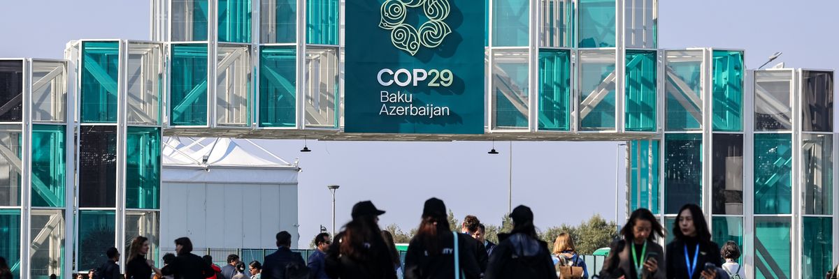 Participants walk by an entrance of COP29 in Baku, the capital of Azerbaijan