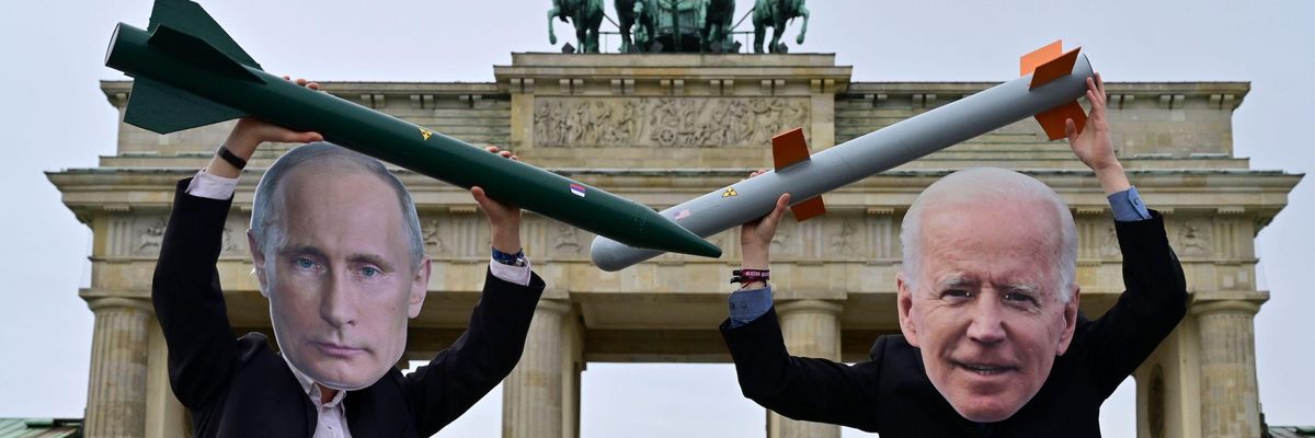 Peace activists wearing masks of Putin and Biden pose with mock nuclear missiles
