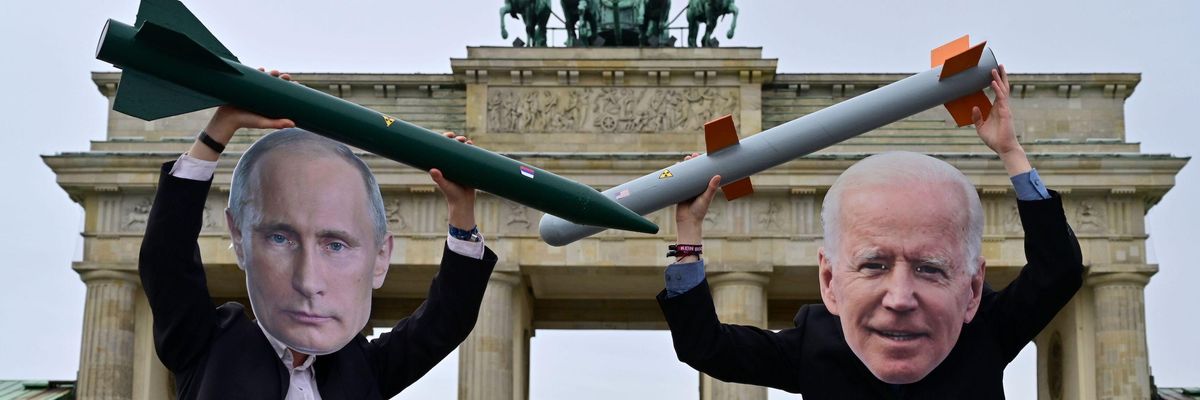 Peace activists wearing masks of Putin and Biden pose with mock nuclear missiles