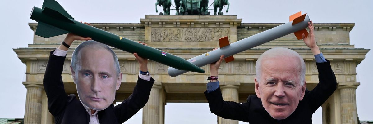 Peace activists wearing masks of  Putin and Biden pose with mock nuclear missiles
