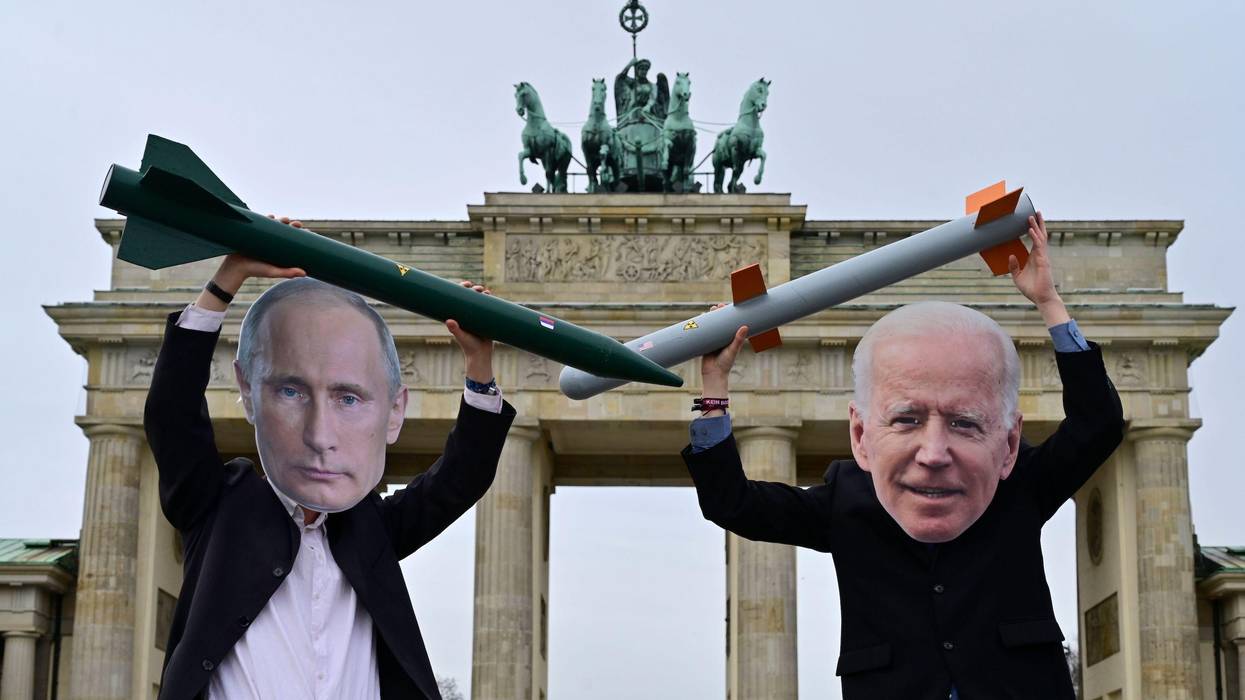 Peace activists wearing masks of Putin and Biden pose with mock nuclear missiles