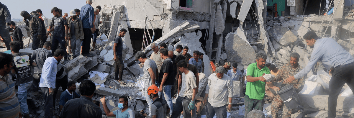 People are seen amid the rubble of a bombed girls' school in Minab, Iran