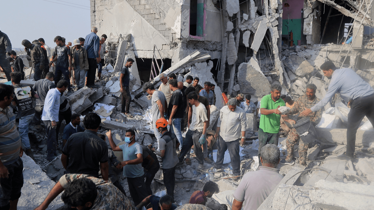 People are seen amid the rubble of a bombed girls' school in Minab, Iran