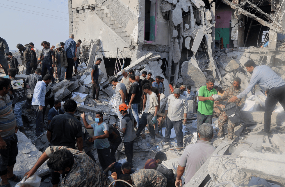 People are seen amid the rubble of a bombed girls' school in Minab, Iran