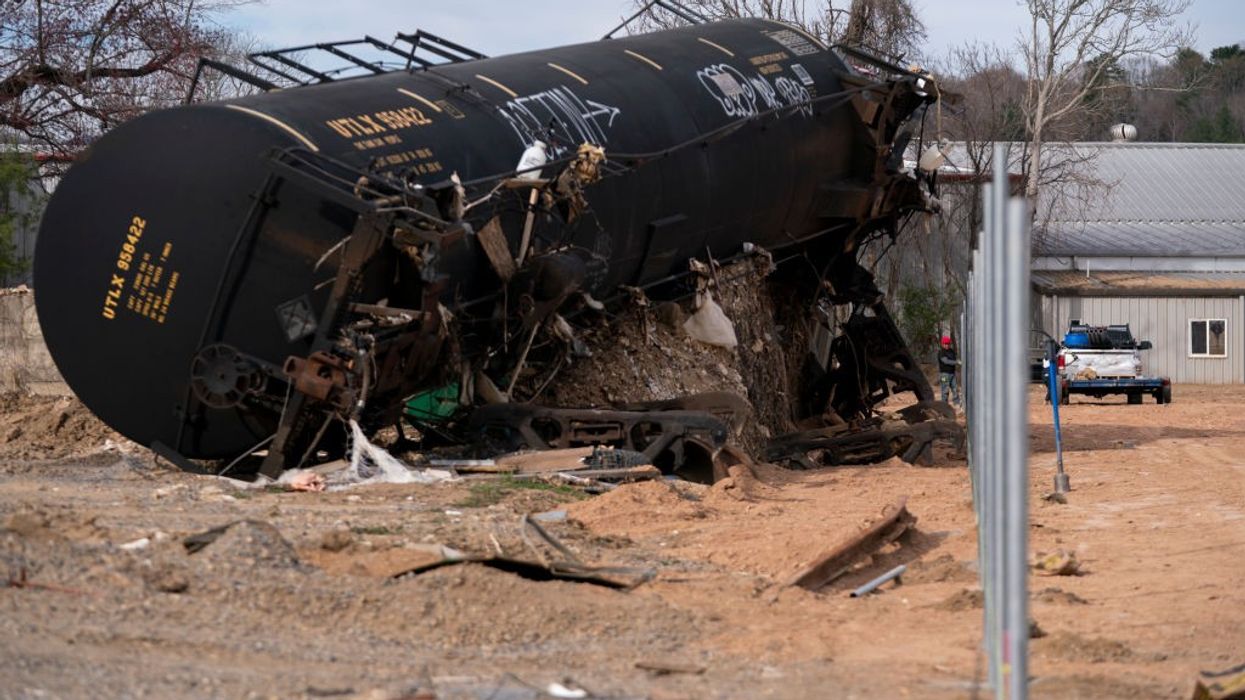 People build a fence near the Swannanoa River in a landscape scarred by Hurricane Helene