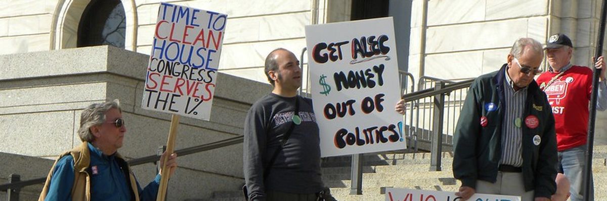 People carry signs protesting ALEC and money in politics.