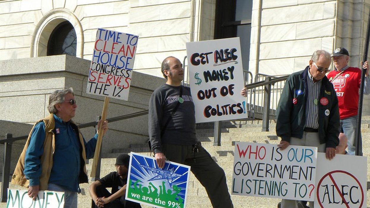 People carry signs protesting ALEC and money in politics.