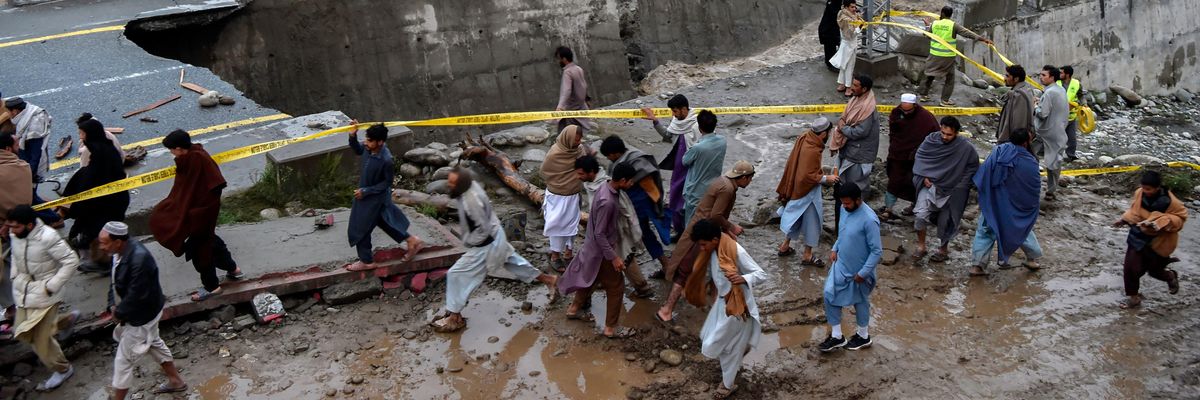 People gather in front of a road damaged by heavy monsoon rains in Madyan, Pakistan on August 27, 2022.