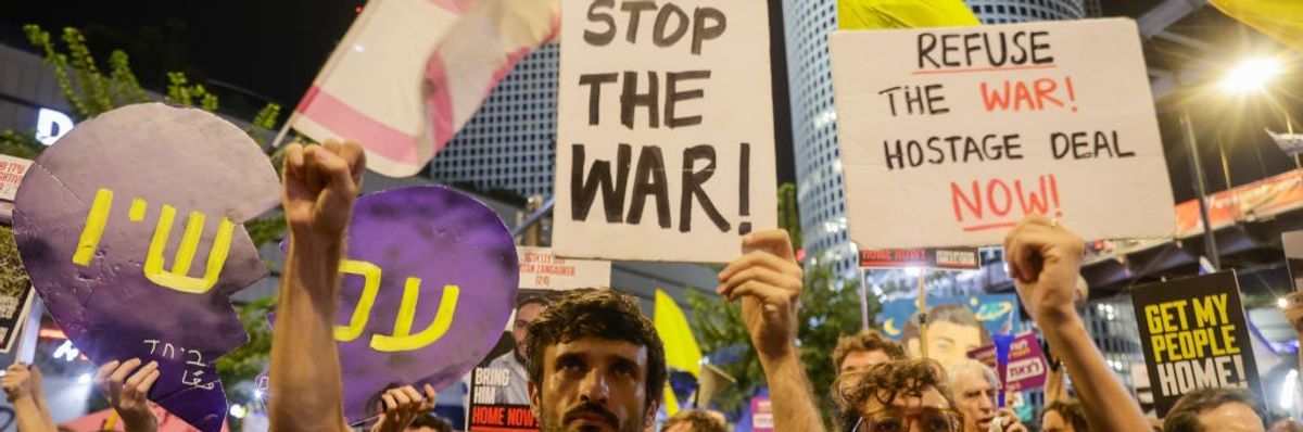 People gather with banners and flags to protest against Israeli Prime Minister Benjamin Netanyahu