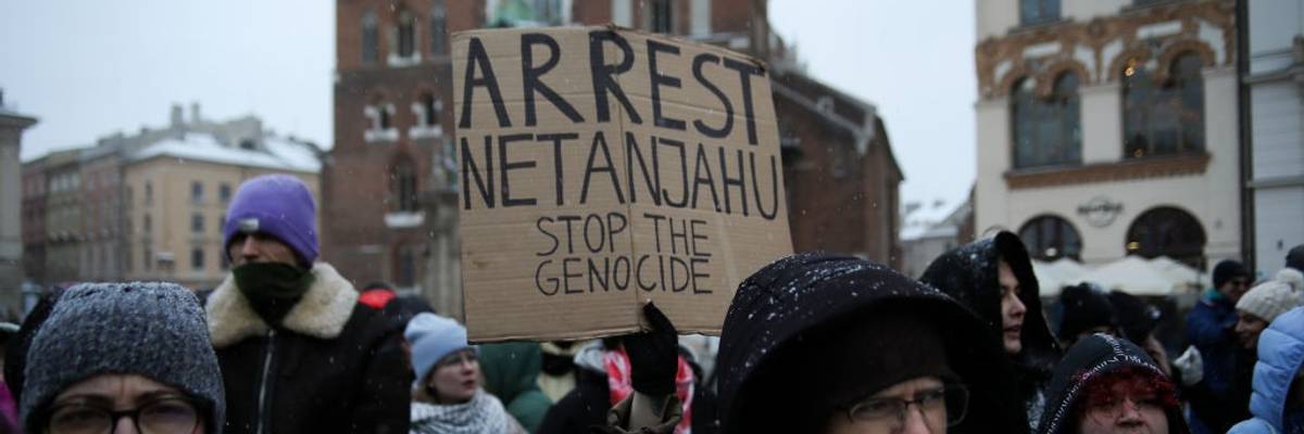 People hold a sign reading, "Arrest Netanyahu stop the genocide."
