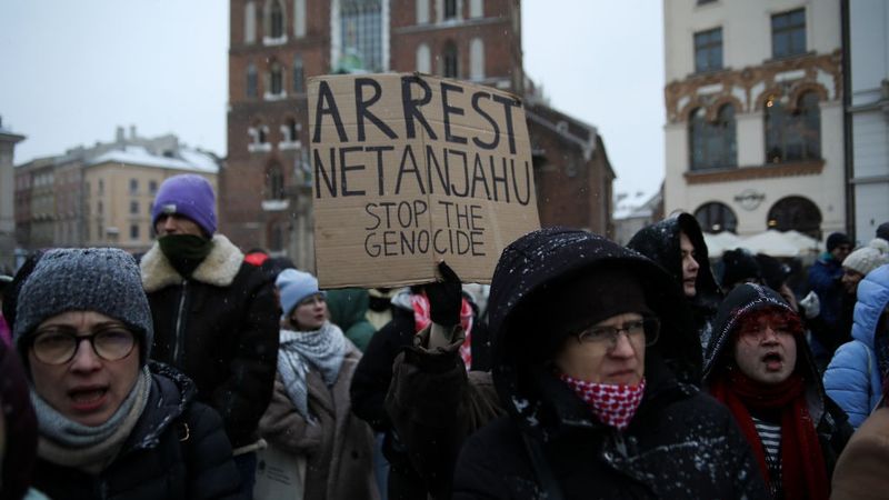 People hold a sign reading, "Arrest Netanyahu stop the genocide."