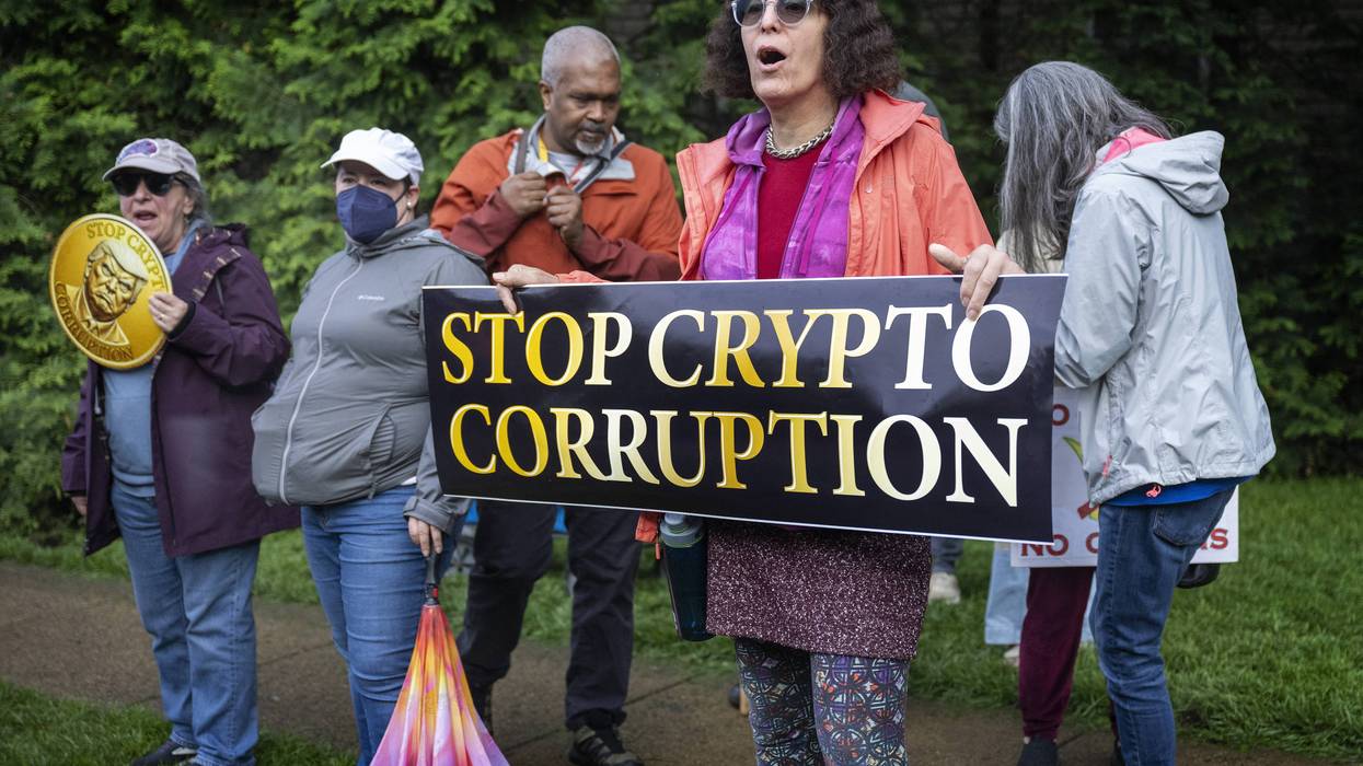 People hold a sign reading "Stop Crypto Corruption"