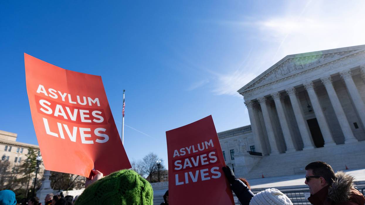 People hold "Asylum Saves Lives" posters outside the Supreme Court.