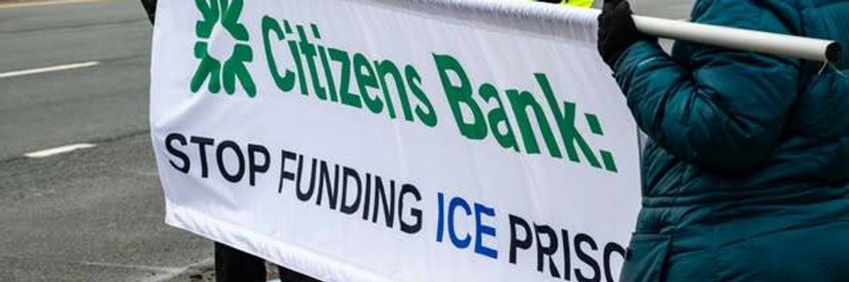 People hold banner calling on Citizens Bank to stop funding ICE prisons.