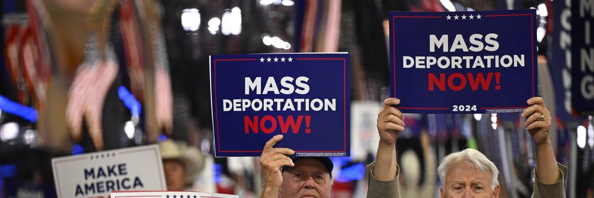 People hold "mass deportations now" signs at the RNC in 2024.