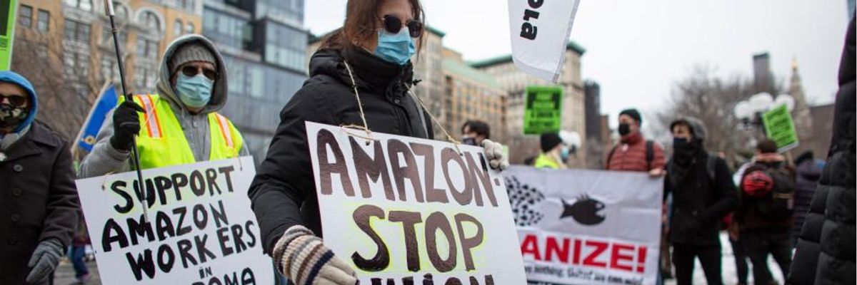 People hold placards during a protest in support of Amazon workers in Union Square, New York on February 20, 2021