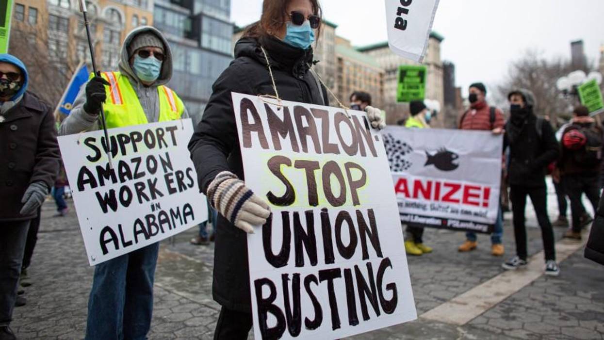 People hold placards during a protest in support of Amazon workers in Union Square, New York on February 20, 2021
