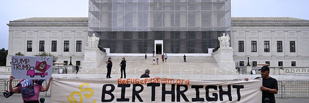 People hold sign defending birthright citizenship in front of Supreme Court.