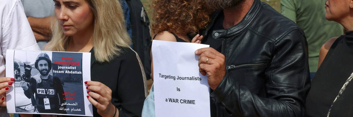 People hold signs and photos of video journalist Issam Abdallah