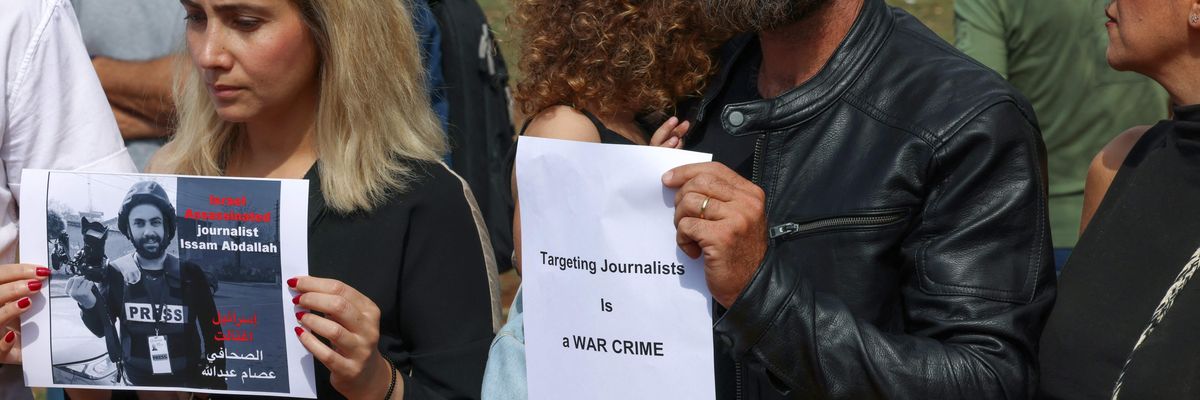 People hold signs and photos of video journalist Issam Abdallah