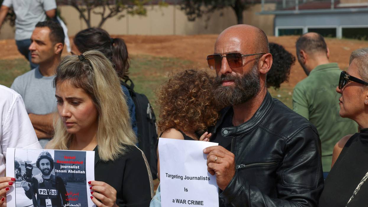 People hold signs and photos of video journalist Issam Abdallah
