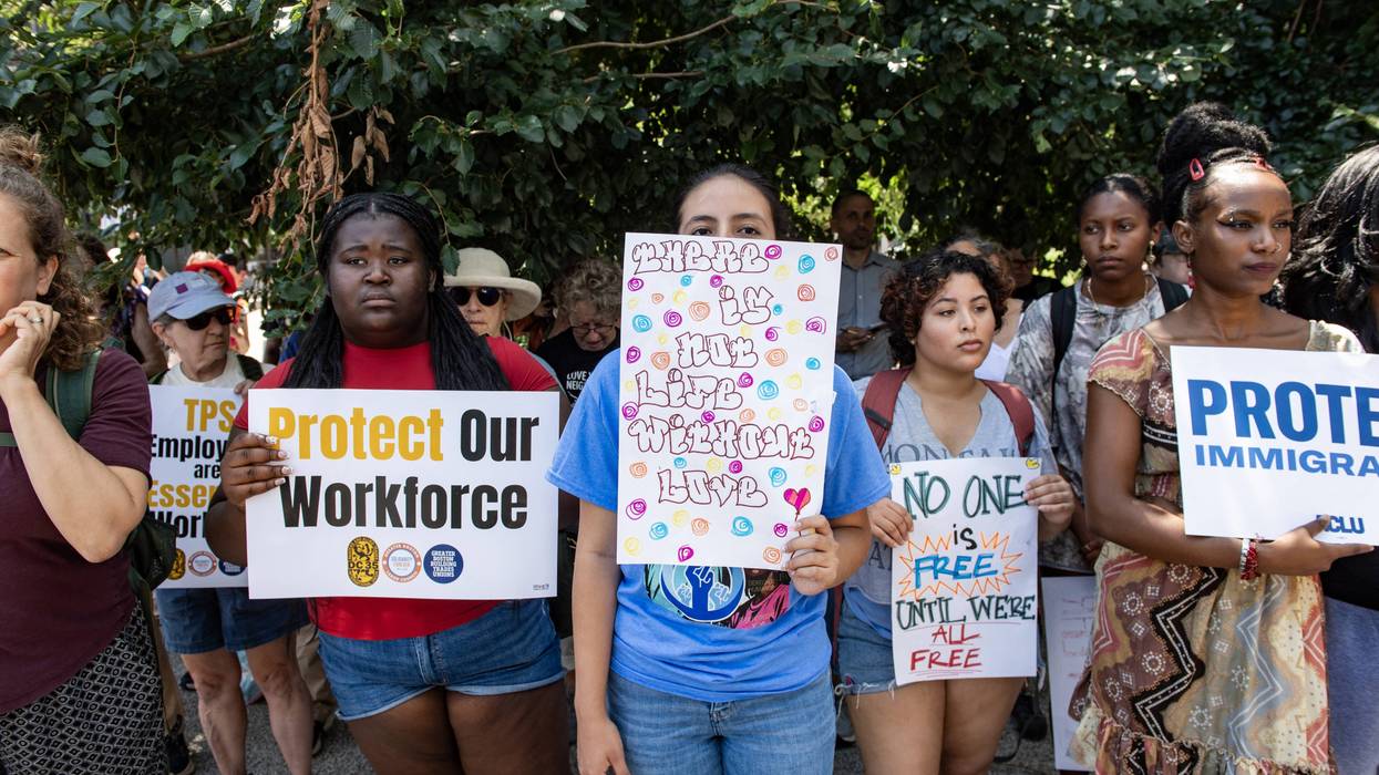 People hold signs at a rally calling on Congress to restore Temporary Protected Status (TPS) for Haitians