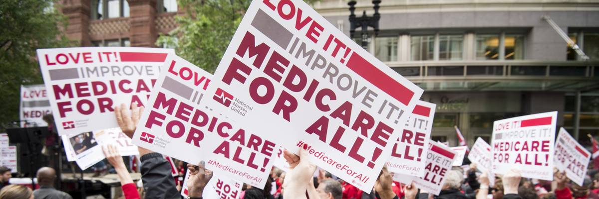 People hold signs calling for Medicare for All