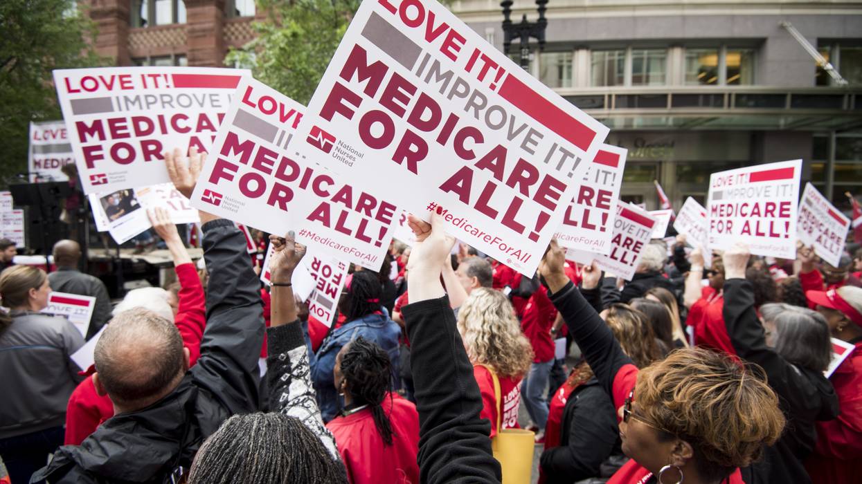 People hold signs calling for Medicare for All