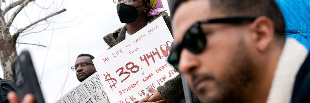 People hold signs during a rally outside the U.S. Department of Education