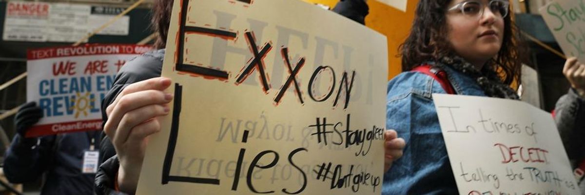 People hold signs in a protest against ExxonMobil.