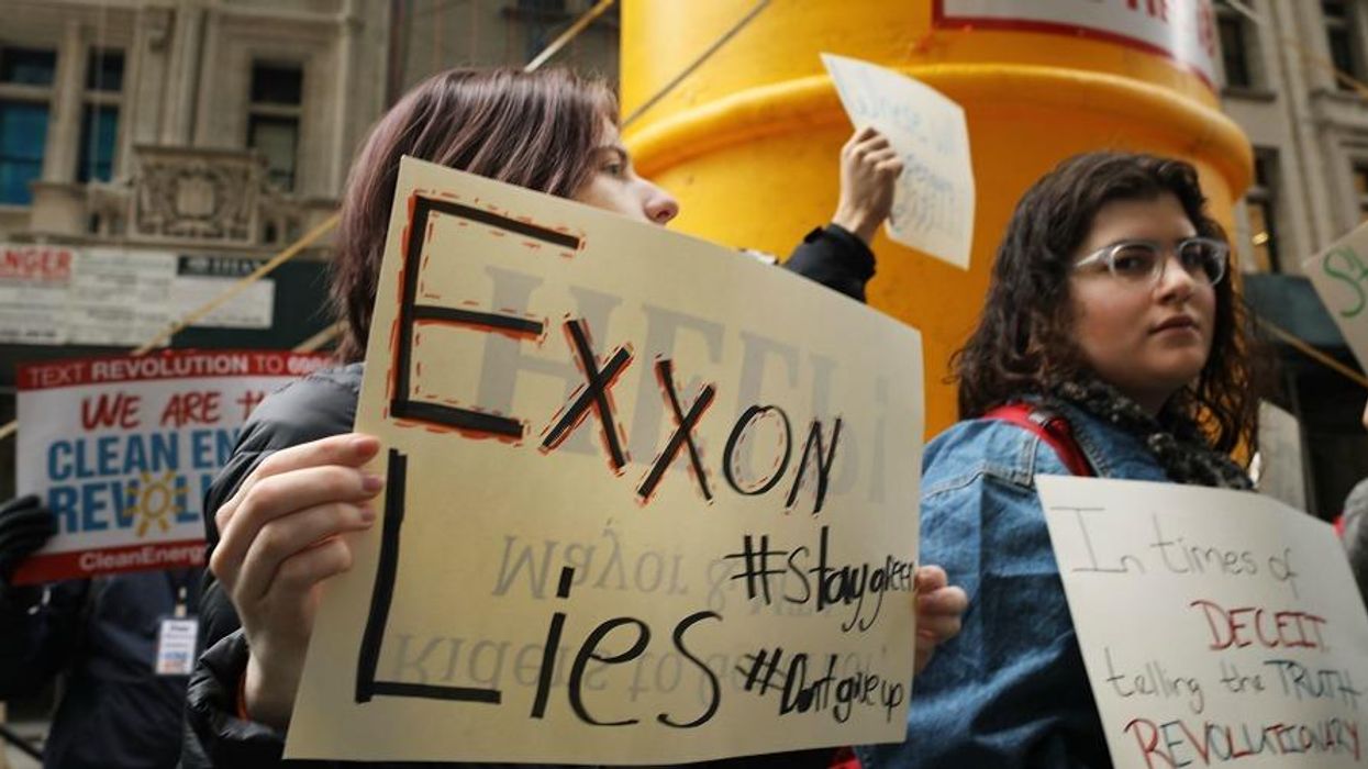 People hold signs in a protest against ExxonMobil.
