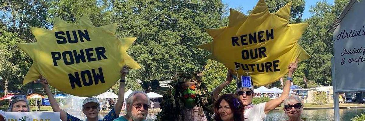 People hold signs promoting solar power and renewable energy.
