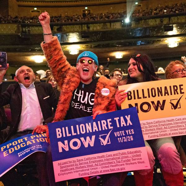 People hold signs reading, "Billionaire Tax Now" during a rally in Los Angeles