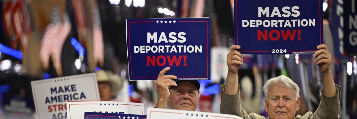 People hold signs reading, "Mass deportations now," at RNC.