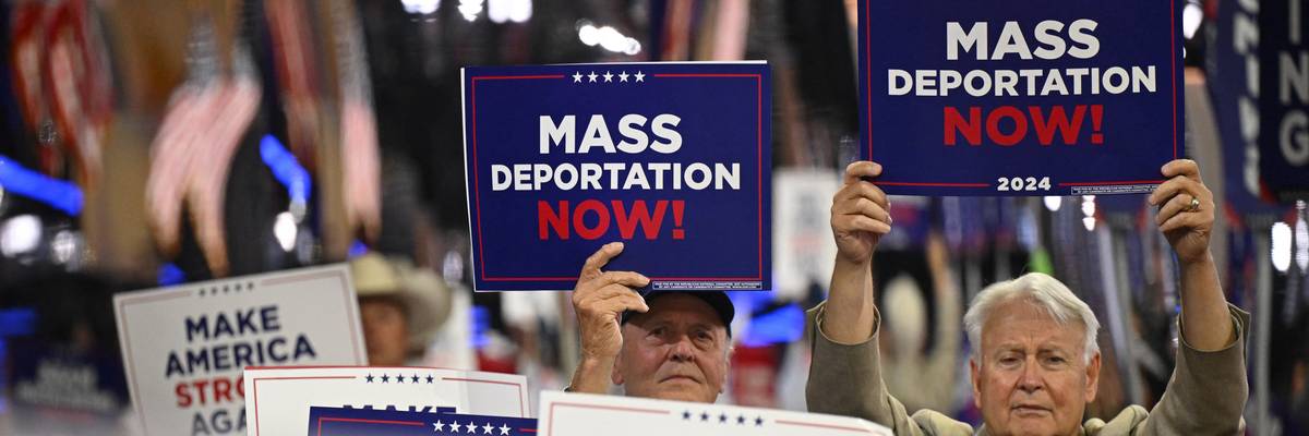 People hold signs reading, "Mass deportations now," at RNC.