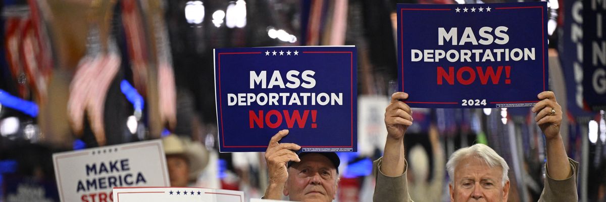 People hold signs reading, "Mass deportations now," at RNC.