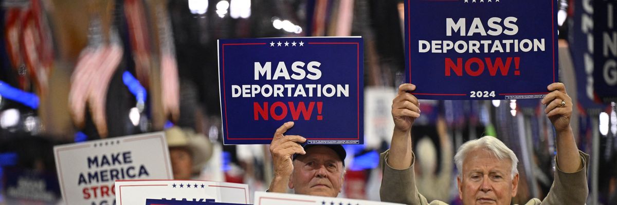 People hold signs reading, "Mass deportations now," at RNC.