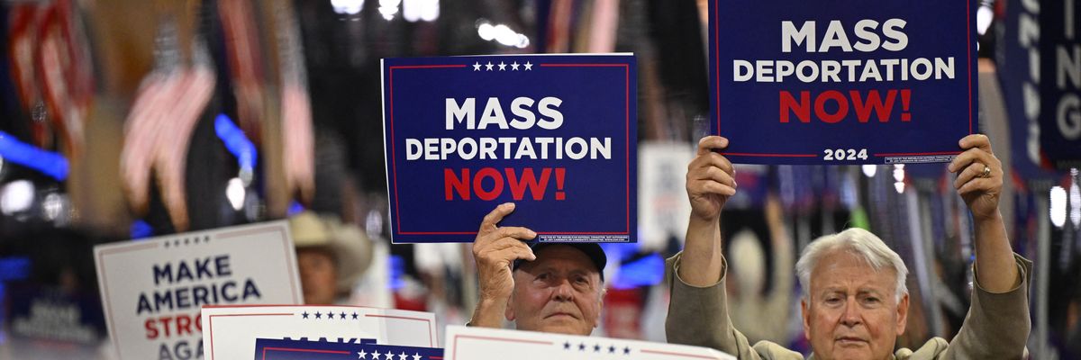 People hold signs reading, "Mass deportations now," at RNC.