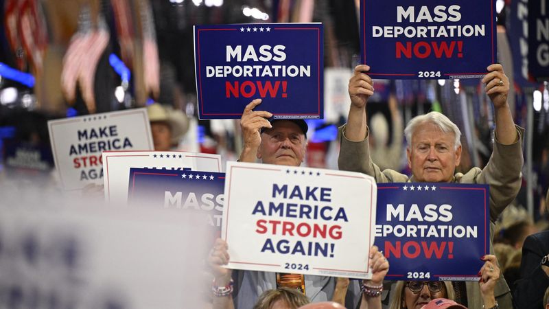 People hold signs reading, "Mass deportations now," at RNC.