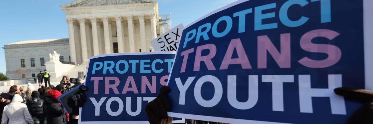 people hold signs reading, "Protect Trans Youth" outside the U.S. Supreme Court