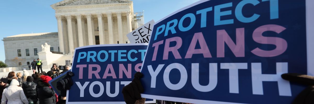 people hold signs reading, "Protect Trans Youth" outside the U.S. Supreme Court